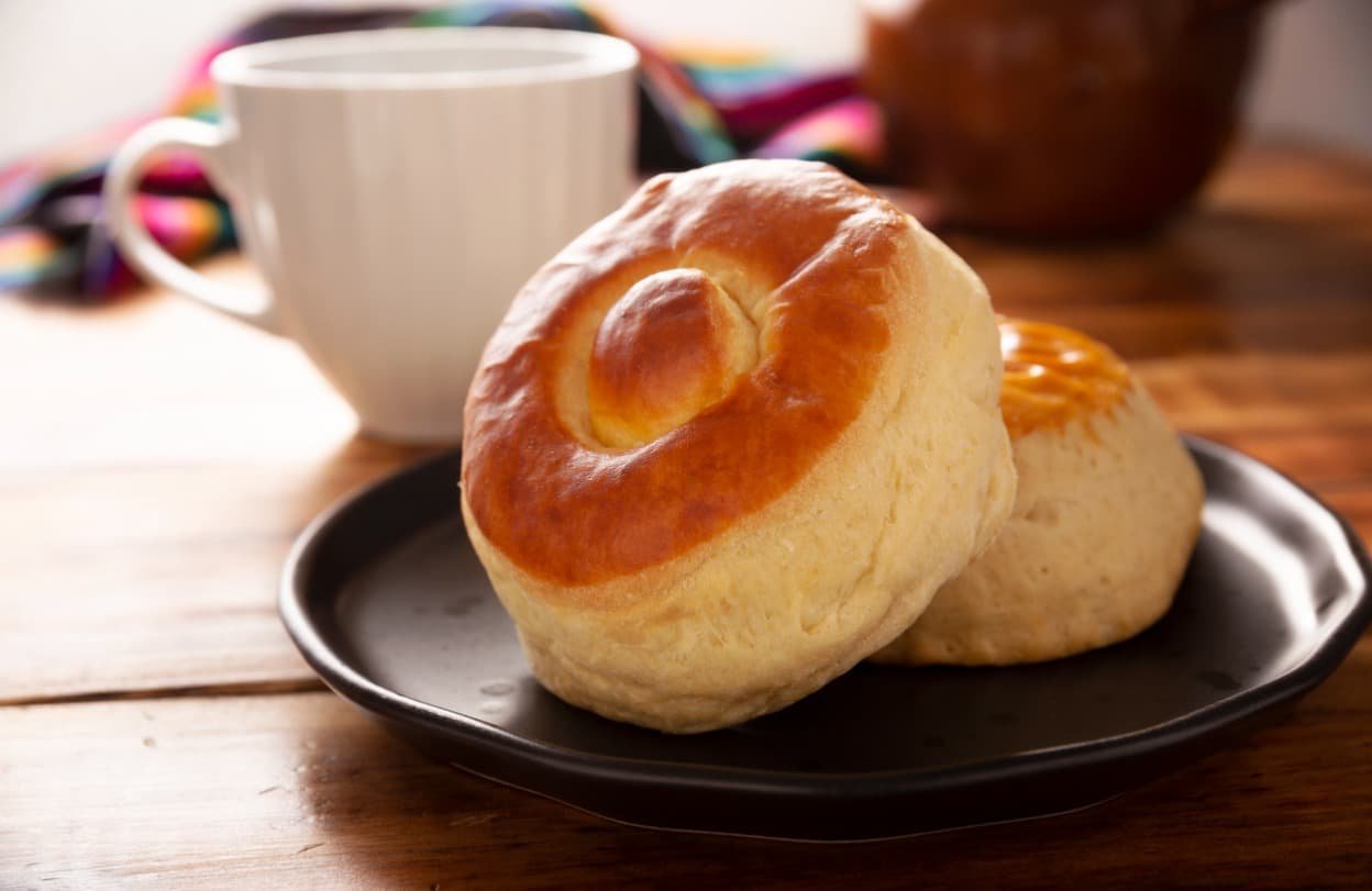Bísquet esponjoso acompañado de café americano recién hecho. Desayuno clásico con pan fresco y café de calidad para comenzar el día con sabor.