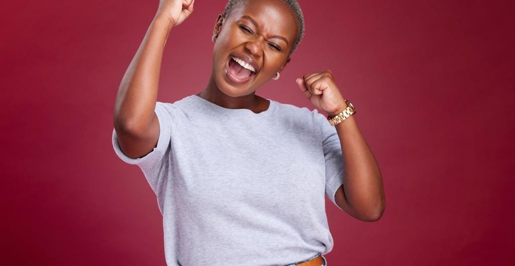 Mujer feliz con fondo rojo levantando las manos de alegría