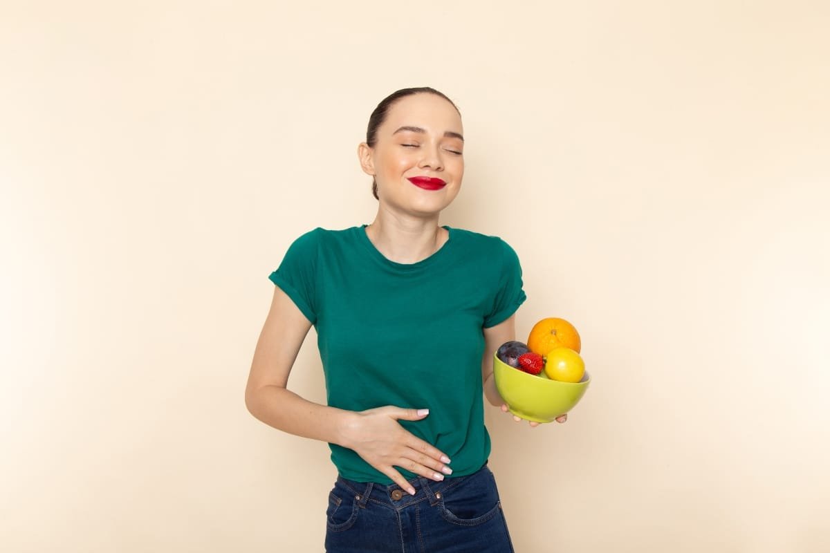 Mujer sosteniendo un tazón de frutas con una gran satisfacción. Estas combinaciones apoyan la salud intestinal, mejoran la digestión y tienen propiedades antiinflamatorias, ideales para mantener el bienestar digestivo.